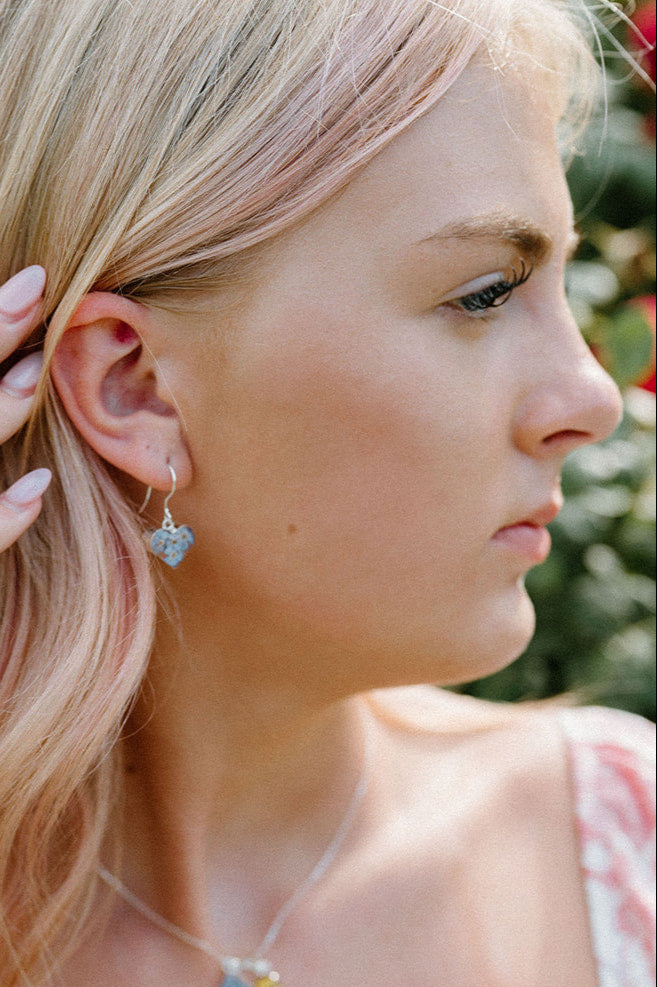Woman wearing colorful jewelry outdoors with greenery in the background