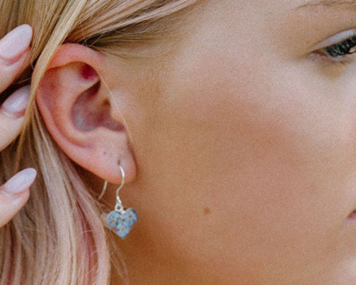 Woman wearing colorful jewelry outdoors with greenery in the background