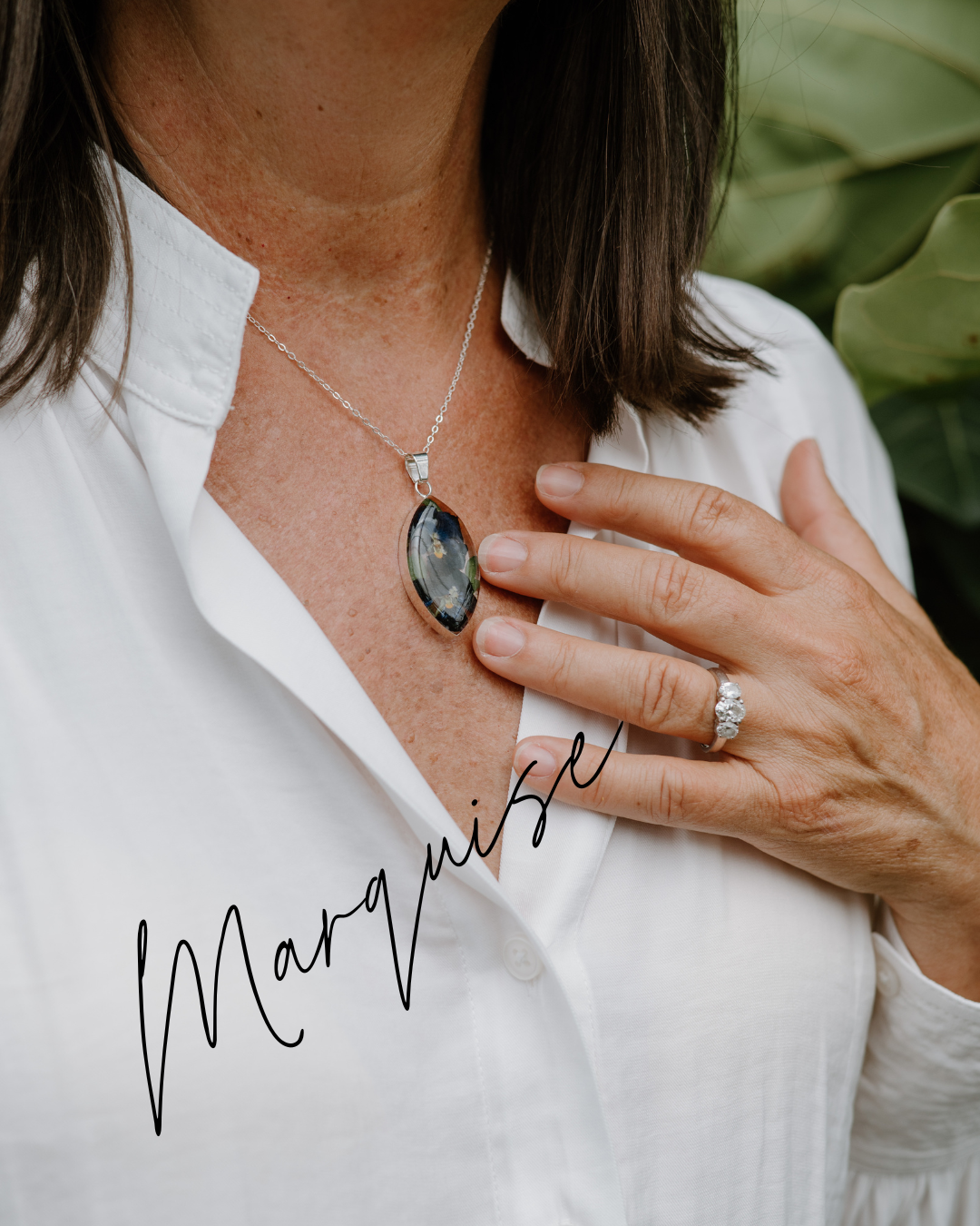 Person wearing a necklace with a pendant and a ring, with 'Marquise' text below.