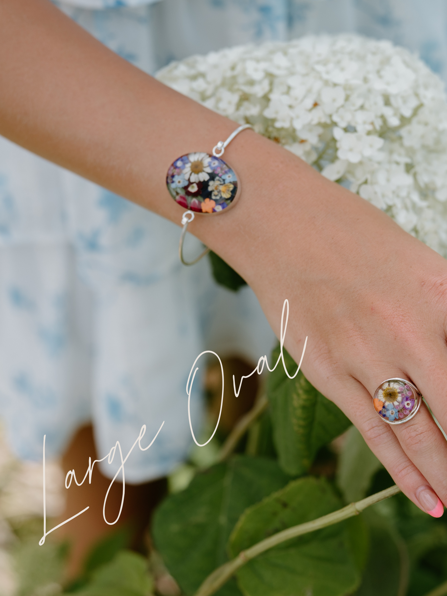 Hand wearing a colorful bracelet and ring with hydrangeas in the background