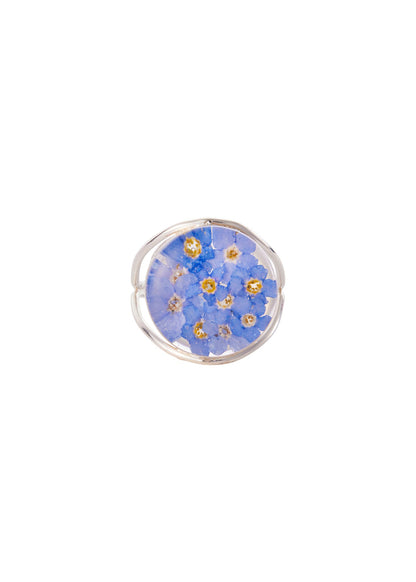 A round sterling silver ring with a medallion-shaped forget me not flower design, set with clear resin-preserved flowers.