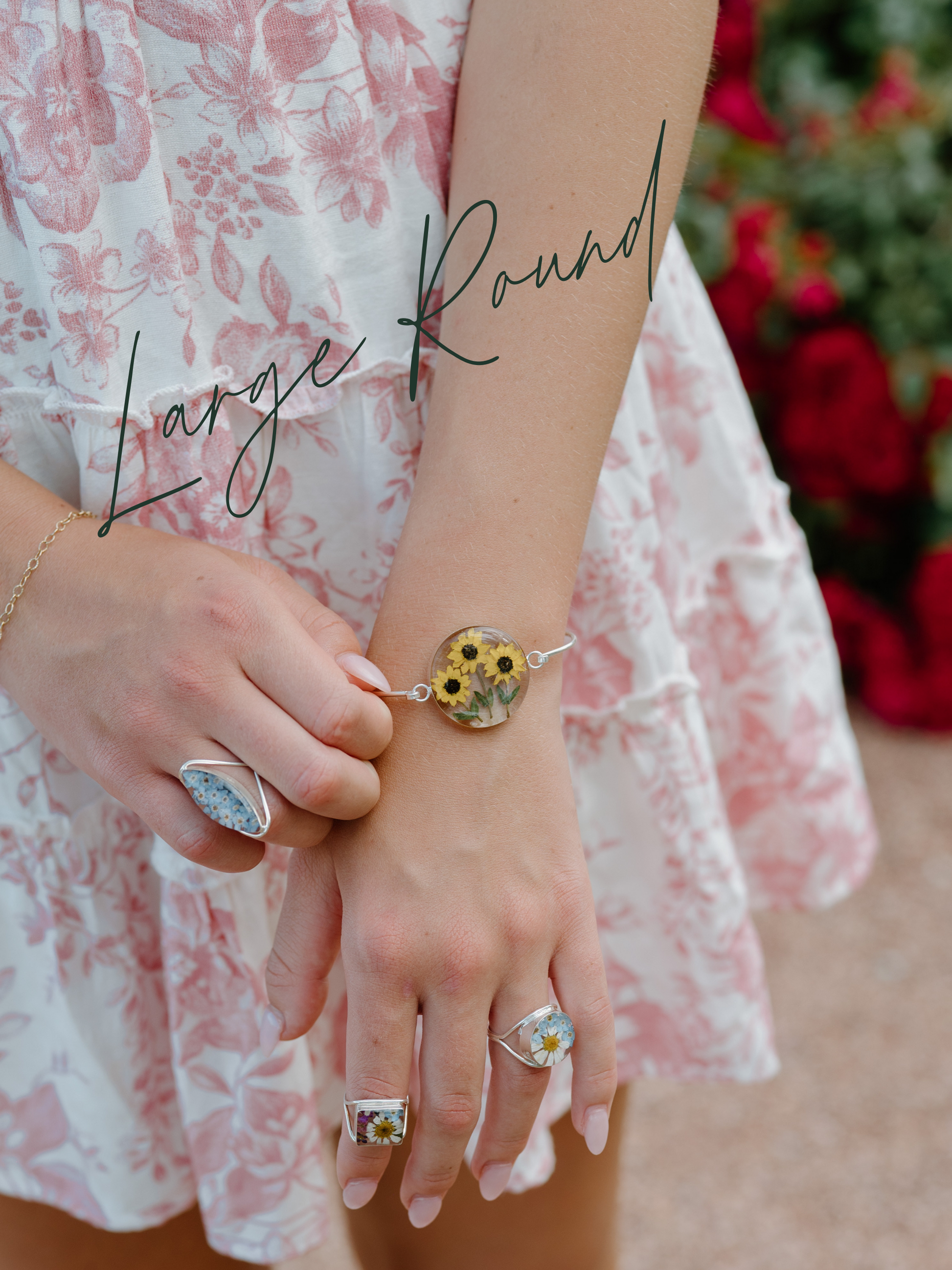 Person wearing a bracelet with a floral design, holding another bracelet, against a blurred background.