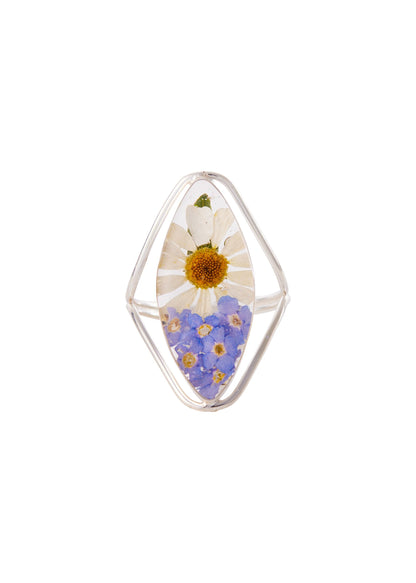 A sterling silver ring with a marquise shape, featuring a daisy and a forget me not flower preserved in clear resin.