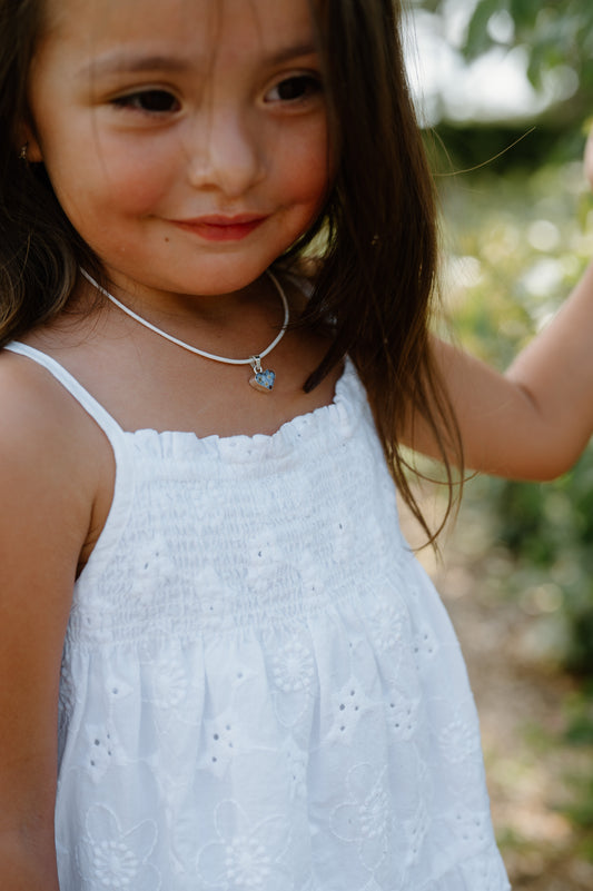 Young girl wearing a white dress with a blurred natural background