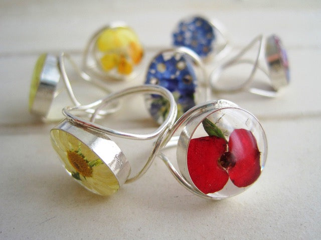 Silver rings with embedded flowers on a light background