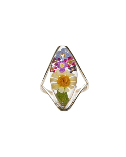 A sterling silver marquise-shaped ring with a daisy and mixed flowers preserved in resin, set against a white background.