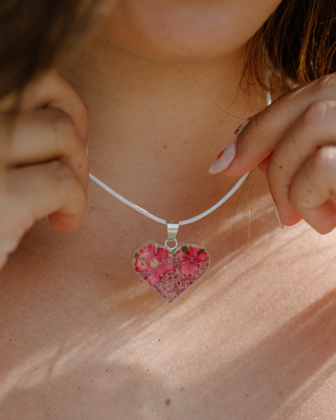 Heart-shaped floral pendant necklace on a person's neck
