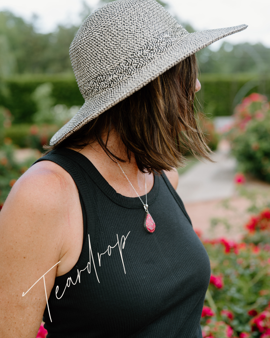 Woman wearing a wide-brimmed hat and black tank top with 'Teardrop' text in a garden setting.