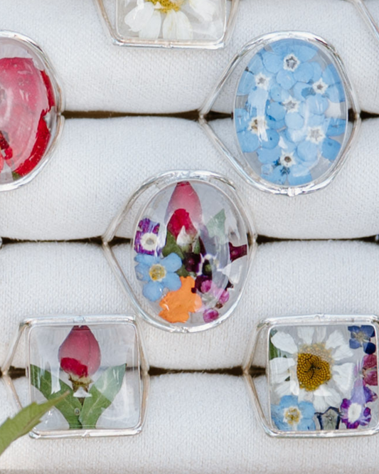 Decorative rings with pressed flowers on a white surface